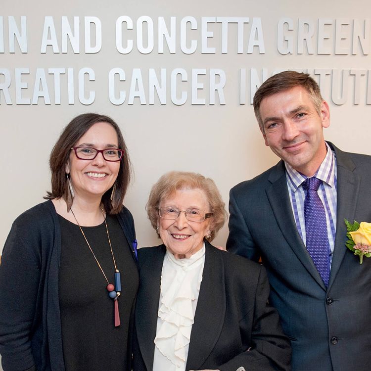 Concetta “Chet” Greenberg and others smile for a photo beneath the Marvin and Concetta Greenberg Pancreatic Cancer Institute sign. 
