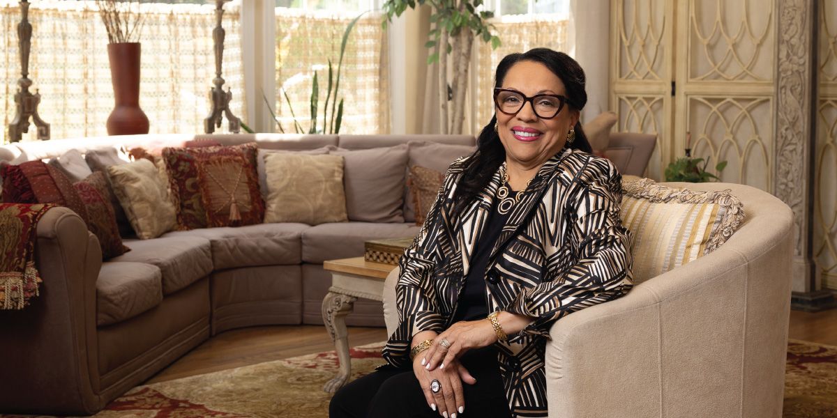 Rose Phillips sitting in an armchair in her home smiles happy for a photo.