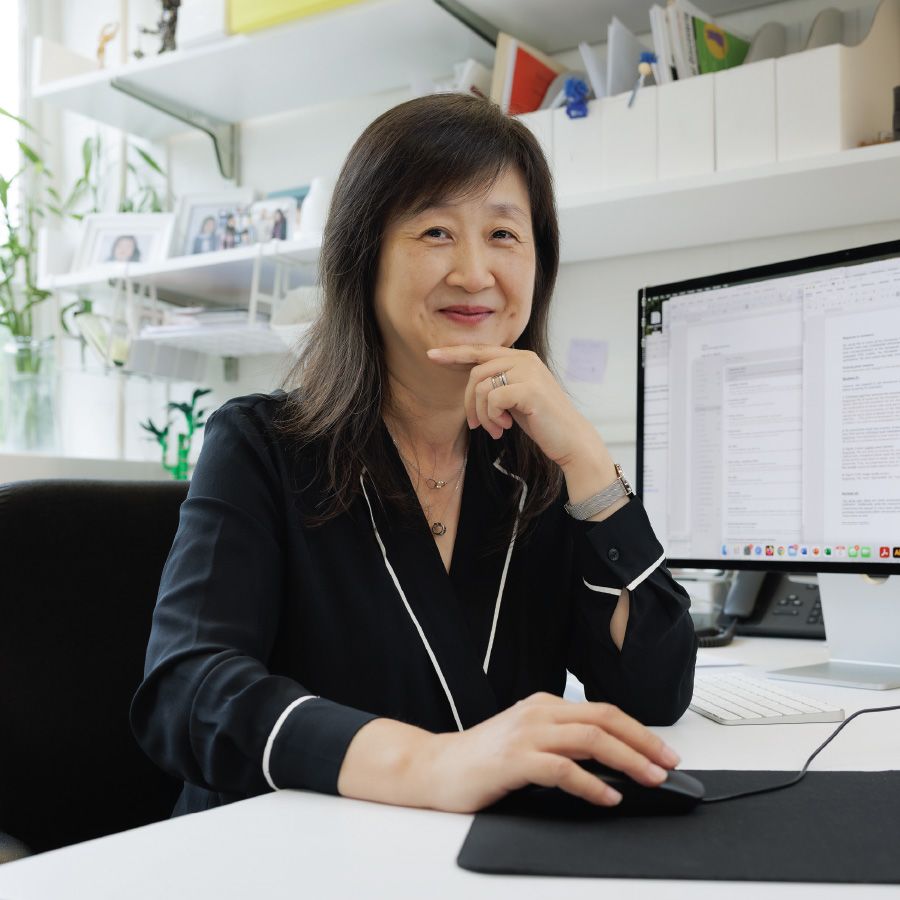Qing Chen, MD, PhD sits at her office desk and pauses her work to smile for a photo.